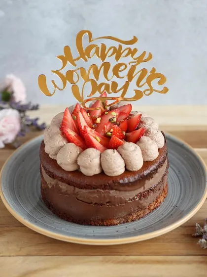 Celebrate the amazing women in your life with this beautiful Women's Day cake, topped with fresh strawberries and a "Happy Women's Day" topper.