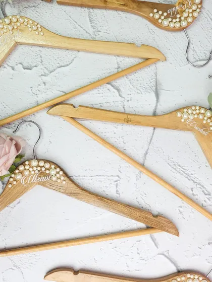 Don't forget the small details. These custom wooden hangers, embellished with pearls and personalized with names, are a beautiful keepsake for the bride and her bridesmaids to hang their dresses on.