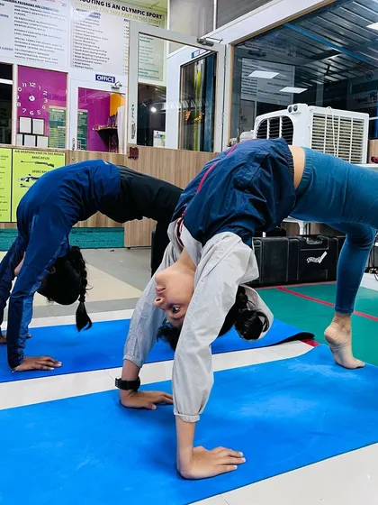 Students practicing the wheel pose during a yoga session at the academy. Yoga improves flexibility and back strength, which is crucial for maintaining a shooting stance.