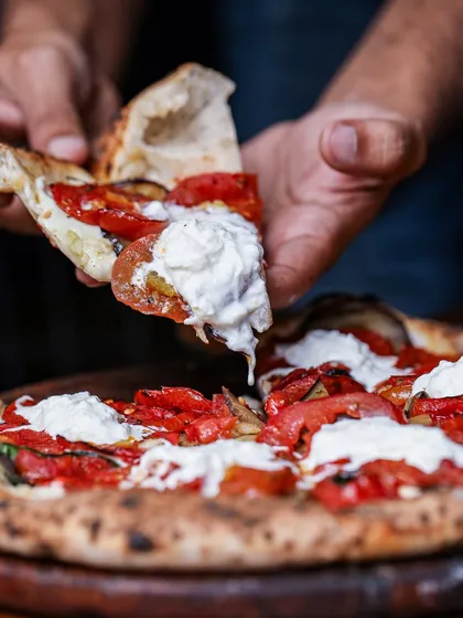 It's all about that perfect bite. A slice of our pizza topped with creamy, hand-pulled burrata shows our commitment to fresh, high-quality ingredients that make every pizza unforgettable.