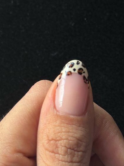 A close-up of the thumb nail, showing the detailed, hand-painted leopard spots.