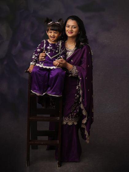 A beautiful mother-daughter portrait in matching traditional purple outfits. The daughter's happy laugh makes this a truly special and memorable photo.