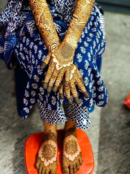 A full view of a bridal design that includes personalized Marvel logos, with matching feet henna.