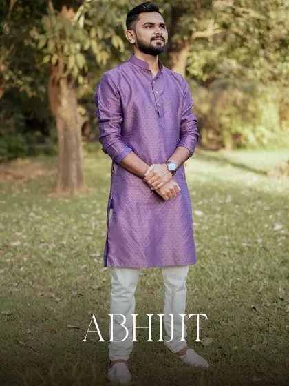 A full-length portrait of the groom, Abhijit, looking sharp in his purple silk kurta.