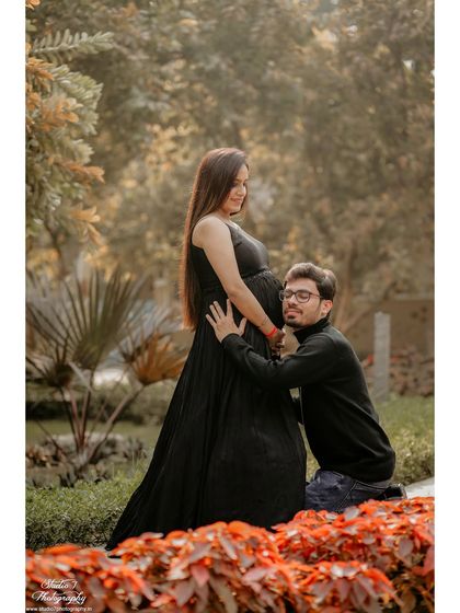 A tender moment captured between the couple, surrounded by the warm tones of an autumn park setting. The focus is on their connection and the baby on the way.