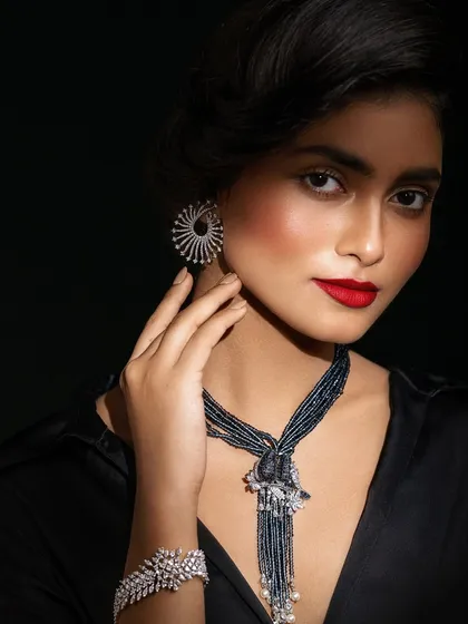 A dramatic close-up with shadow play, focusing on the striking earrings and bold red lip.