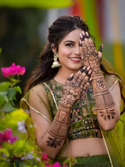 A happy bride posing with her storybook mehndi. The design features panels with different portraits and symbols, telling a story that is unique to her.