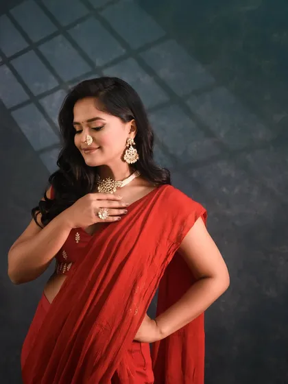 A close-up of the red sharara-saree look, highlighting the statement jewellery and nath.
