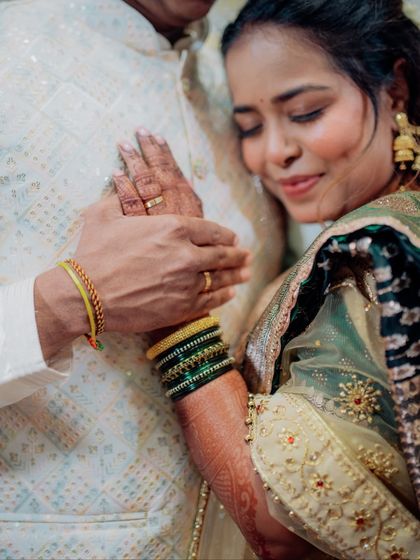 A close-up shot focusing on the details of an engagement: the intricate henna on her hands, the traditional green bangles, and the gentle way they hold hands, signifying their new bond.