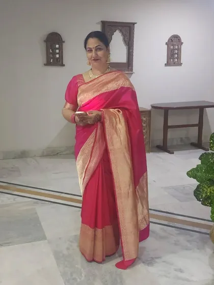 A full-length shot of the mother of the bride, looking graceful and elegant in a pink silk saree.
