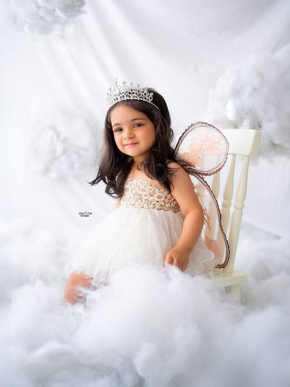 A poised and pretty angel sitting on her chair in the clouds.