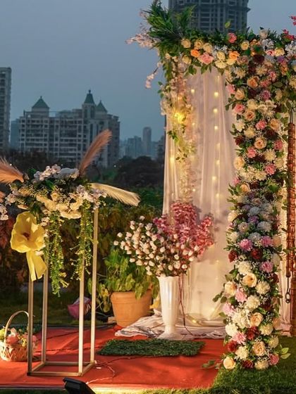 This angle showcases the depth of the outdoor setup, with the floral arrangements in the foreground and the decorated swing against the city lights in the background. It highlights the layers of detail in the decor.