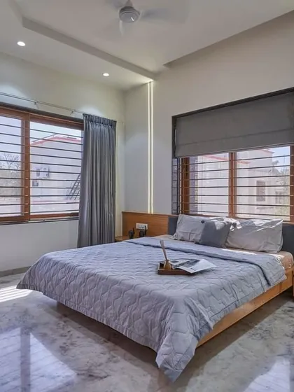This bedroom is all about clean lines and natural light. The simple wooden bed frame and integrated headboard are complemented by vertical light strips that add a touch of modern ambiance.