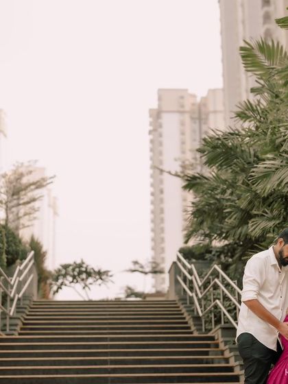 An urban-style maternity shoot for a modern couple. The leading lines of the staircase and the contrast between the greenery and architecture create a dynamic and stylish backdrop for their portrait.