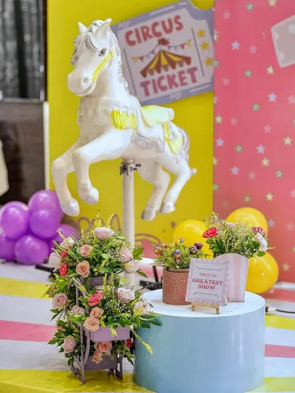 A beautiful floral arrangement sits next to a carousel horse prop at a carnival-themed event. This shows how I blend elegant details with playful, thematic elements.