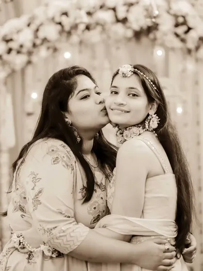 A tender moment between sisters at the Haldi ceremony. A sweet kiss on the cheek shows their love and excitement for the bride.