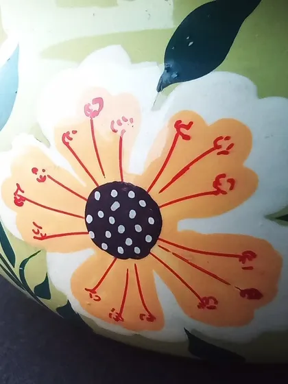A close-up of a hand-painted floral motif on a light green vessel, showcasing the delicate brushwork.