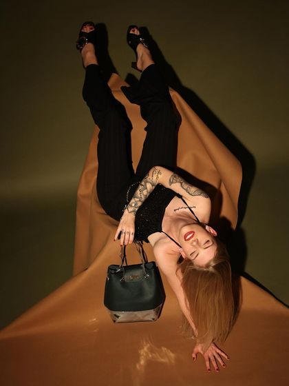 This unconventional, artistic pose was designed to be disruptive and eye-catching for a social media campaign. It showcases the handbag from a unique angle while creating a memorable, high-fashion image.