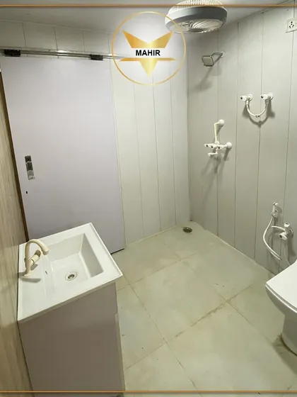 This is a look inside a fully-equipped container bathroom. It features a modern vanity, a western toilet with a health faucet, and a shower area, all built with durable, easy-to-clean materials for a comfortable and hygienic experience.