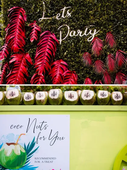 It's all in the tropical details. A "Lets Party" sign with vibrant red leaves and a row of fresh coconuts branded with the couple's anchor logo, ready to be served as refreshing welcome drinks.