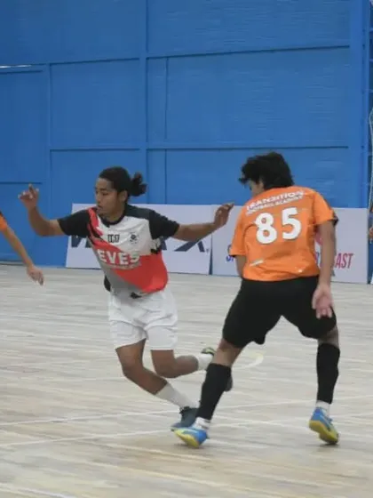 A player shields the ball during a competitive futsal match, showcasing strength and control.