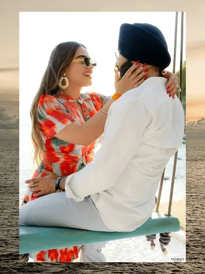A joyful portrait of the couple on a beach swing, framed by the sea.