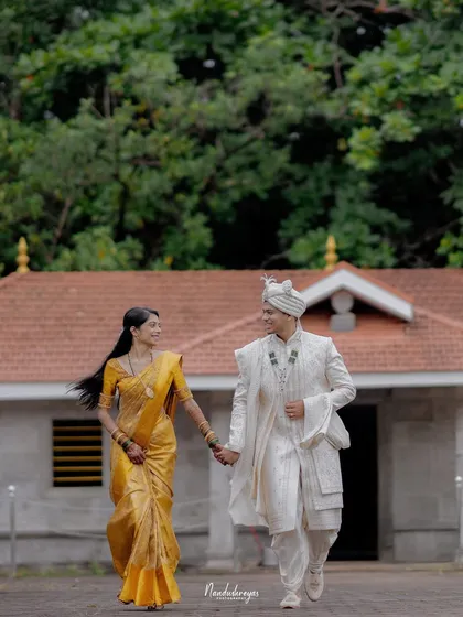 A couple walks hand-in-hand away from a traditional building towards the viewer, a beautiful motion shot from their riverside session.