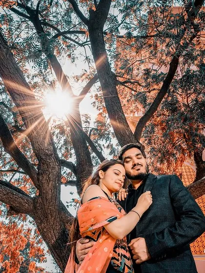 A sun-kissed embrace under a sprawling tree, with the heritage architecture in the background. This shot perfectly blends nature with royal history.