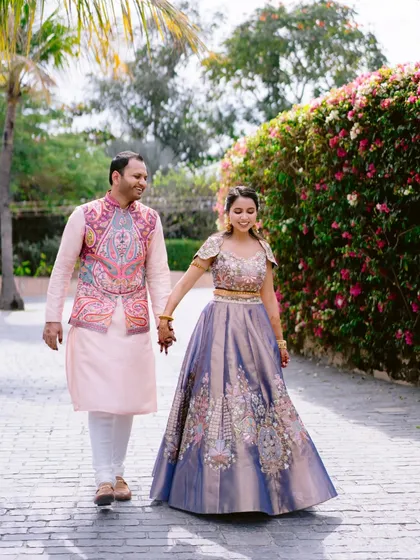 The couple walks hand-in-hand through the beautiful grounds of the Radisson Blu Udaipur, with its lush gardens and classic architecture.