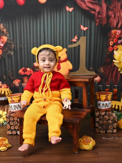 Our little Winnie the Pooh, ready for an adventure. The detailed backdrop and props bring this beloved story to life for a magical first birthday photoshoot.