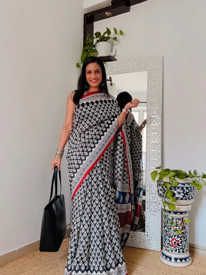 This black and white saree with a red border is a classic combination. The print is sharp and modern, making it a versatile addition to any workwear collection.