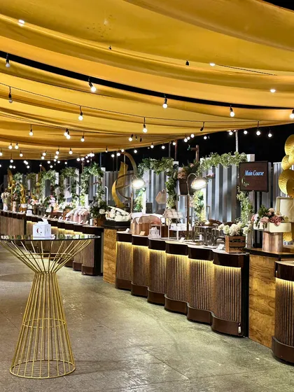 We create magical ambiances with thoughtful lighting and decor. Draped ceilings with string lights cast a warm glow over our elegantly arranged food stations, perfect for an evening of celebration.