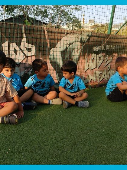 Making memories on the field. A group of boys sits together on the turf, chatting and laughing between drills. These moments of friendship are just as important as the football.
