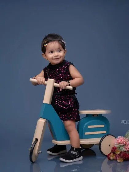 The color version of the scooter portrait, set against a deep blue background. The simple, elegant setup highlights the child's sparkly dress and happy mood.