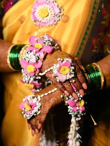 A detailed shot of the bride's hands, adorned with intricate hathphool. The pink and yellow flowers with mogra buds are a classic combination for any Haldi look.