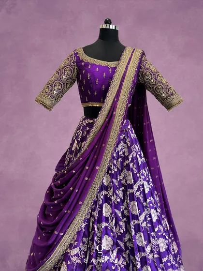 A symphony of royal purple and gold. This custom lehenga features intricate floral embroidery and a beautifully draped dupatta, designed to make a grand statement at any celebration.