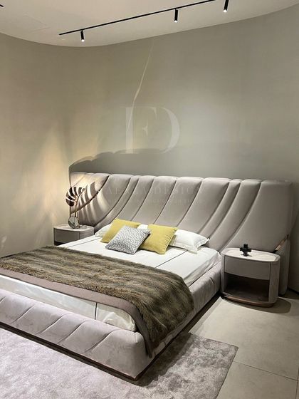 A full view of the bed with the dynamic, diagonally-tufted headboard. The matching upholstered base and custom side tables with marble tops create a complete, high-end look.