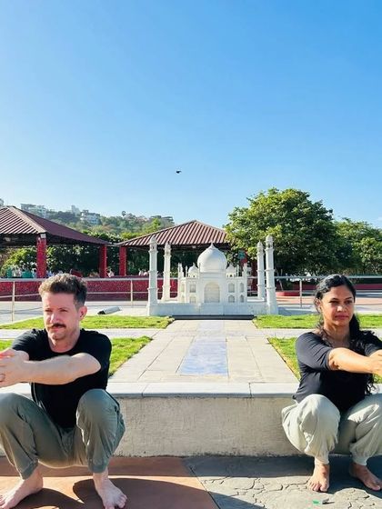 Doing a simple squat in front of a miniature Taj Mahal. This shows that the principles of yoga can be applied anywhere, reminding us to stay grounded and connected to our bodies.