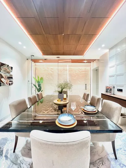 A close-up of the dining table, showcasing the reflective quality of the polished black marble. The wooden ceiling detail is perfectly mirrored on the surface, demonstrating our attention to material finishes.