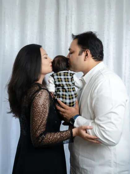 A sweet kiss for the newest family member. This photo beautifully captures the love and affection that parents have for their newborn baby.