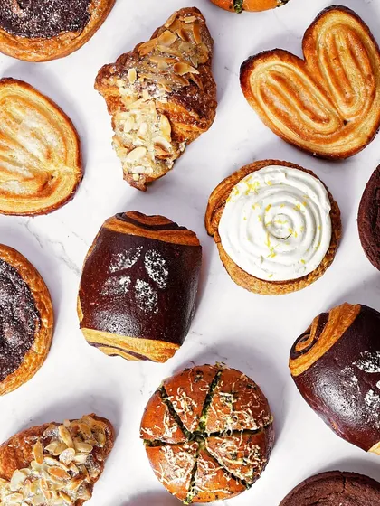 A flatlay of assorted French pastries, including croissants and pain au chocolat, on a clean white marble background. This shot is perfect for showcasing a bakery's variety.