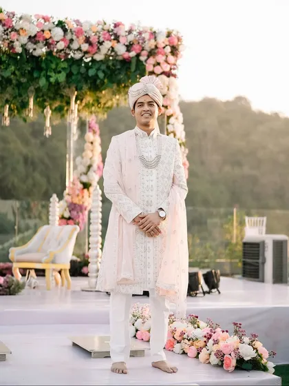 The groom stands proudly at his mandap, looking regal in his pastel sherwani. A moment of calm before the celebrations begin.