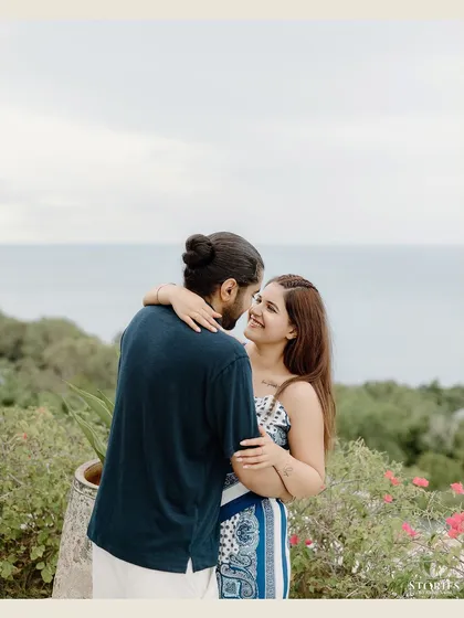 A happy, candid portrait of the couple on their balcony overlooking the sea.