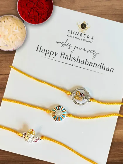This flat lay showcases three of our popular silver rakhi designs for Rakshabandhan. The set includes a Ganesha motif, a modern circular design, and a 'Veera' rakhi, arranged with traditional rice and kumkum for the ceremony.
