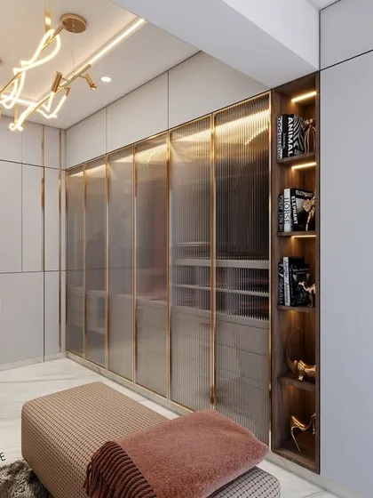 This 3D render showcases a walk-in wardrobe design that balances luxury and function. It features fluted glass doors with brass frames, integrated open shelving for display, and a modern chandelier, all contributing to a high-end, organized space.