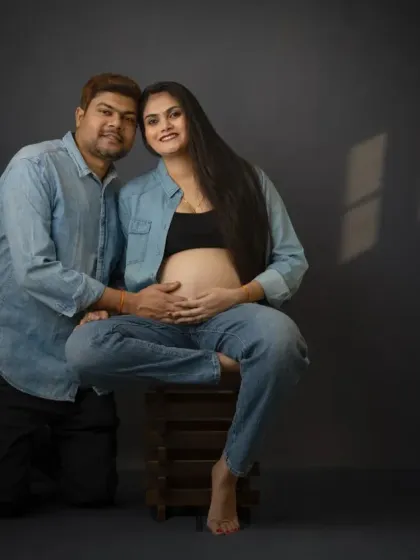 A loving couple's portrait in a casual denim theme. The partner's gentle touch on the baby bump shows their shared journey and excitement.