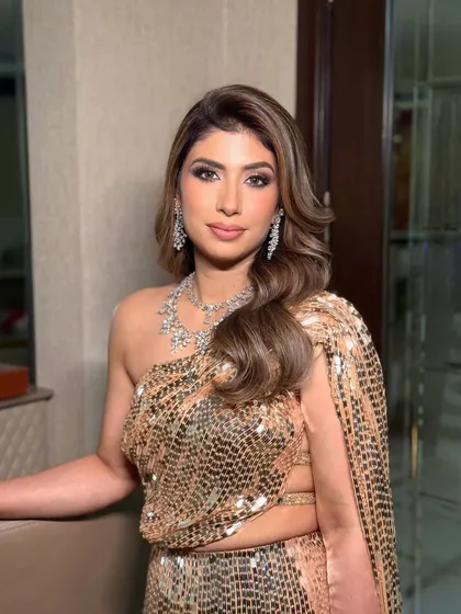 A close-up of the golden glamour look. The makeup features warm, bronzy tones and a perfectly blended smoky eye to complement the high-shine outfit and diamond jewelry.