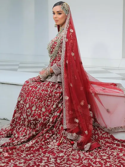 The bride seated, her long, embroidered train spread out beautifully. Her makeup remains the focal point, with a bold eye and luminous skin.