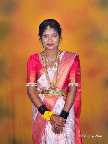 A full-length view of a South Indian bride. Her look is completed with heavy temple jewelry, a waist belt (vaddanam), and traditional black bangles, all part of the classic bridal attire.