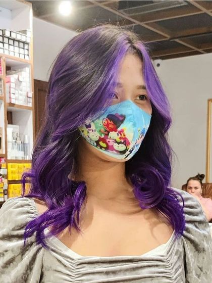 A close-up of a client's vibrant purple hair with face-framing highlights. This style is perfect for making a bold statement with a trendy color.